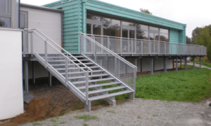 breite Treppe außen mit Geländer um das Gebäude